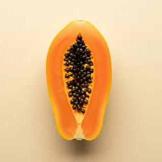 A halved ripe papaya showing the bright orange flesh and the cluster of dark seeds
